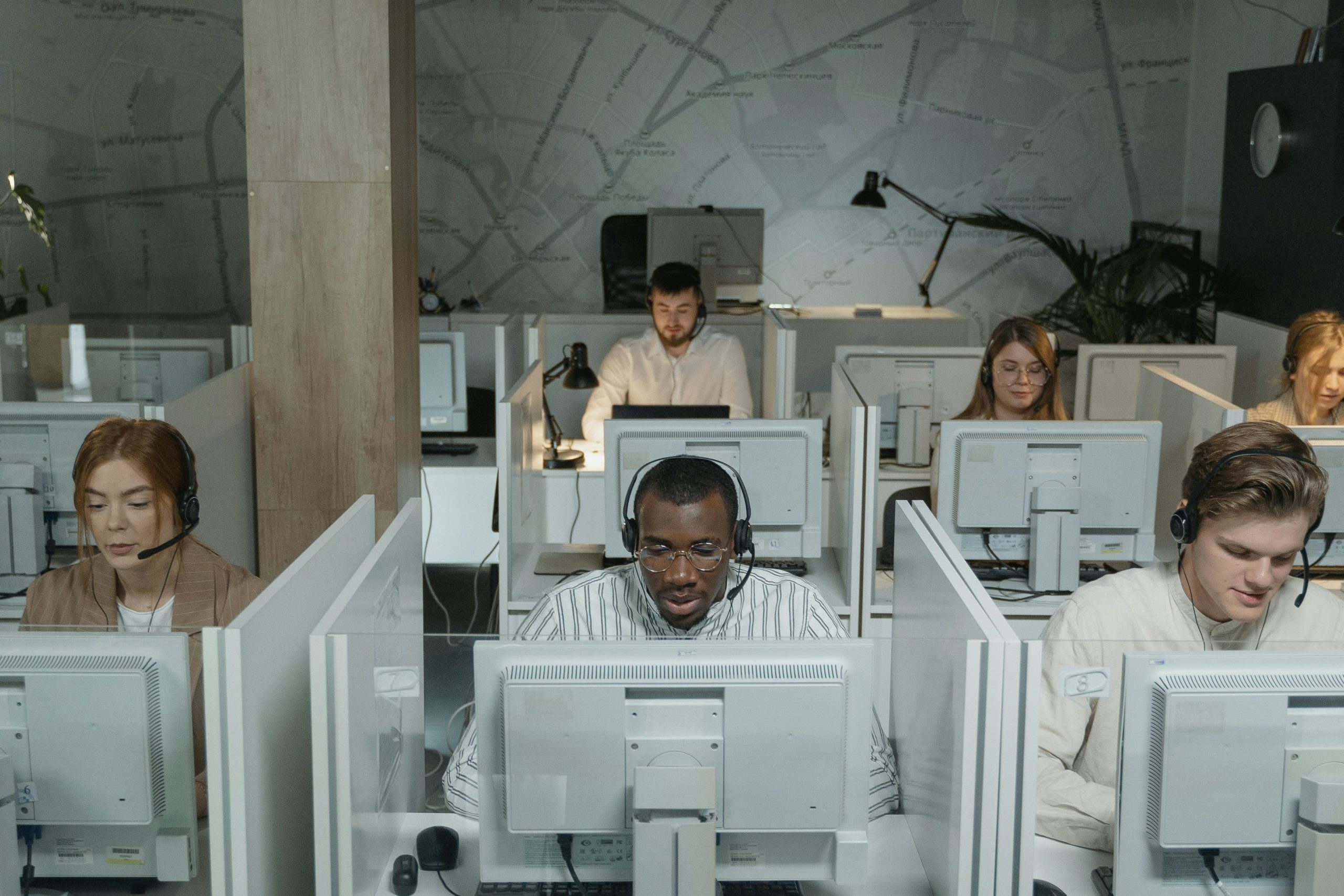 A diverse group of call center agents focused on their computer screens in a modern office setup, illustrating a busy call center environment.